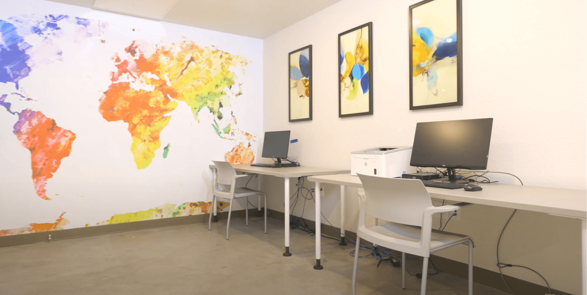 Computer lab -colorful world map mural on wall, three framed images of geometrical art work